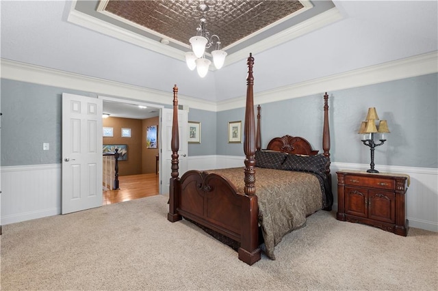 bedroom with a tray ceiling, light carpet, ornamental molding, and an inviting chandelier