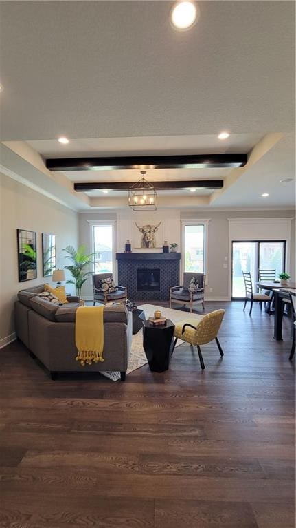 living room featuring beam ceiling, dark wood-type flooring, a tile fireplace, and a wealth of natural light