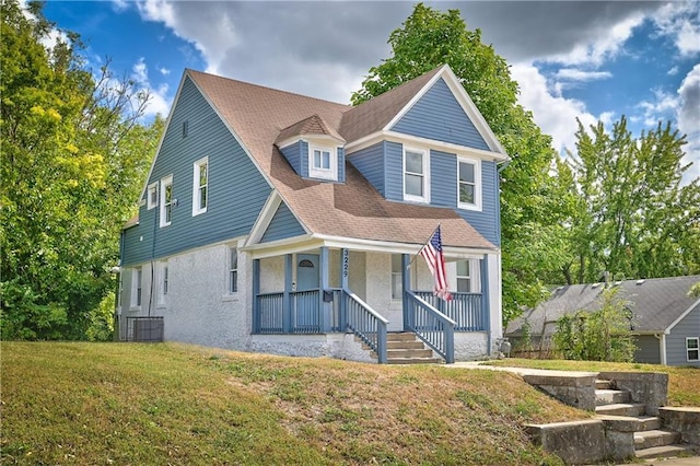3229 Wayne Ave, Kansas City, MO 64109 - view of front facade with covered porch, a shingled roof, and a front lawn