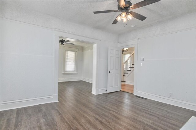 3229 Wayne Ave, Kansas City, MO 64109 - spare room with stairway, ceiling fan with notable chandelier, a textured ceiling, visible vents, and wood finished floors
