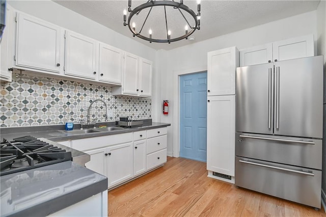 3229 Wayne Ave, Kansas City, MO 64109 - kitchen featuring high quality fridge, white cabinetry, a sink, light wood-type flooring, and a notable chandelier