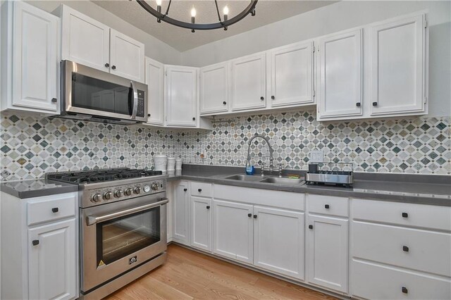 3229 Wayne Ave, Kansas City, MO 64109 - kitchen with white cabinetry, a sink, stainless steel appliances, and dark countertops