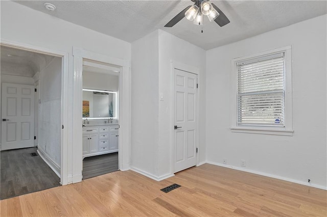 3229 Wayne Ave, Kansas City, MO 64109 - unfurnished bedroom with baseboards, a textured ceiling, ensuite bath, light wood-style floors, and visible vents
