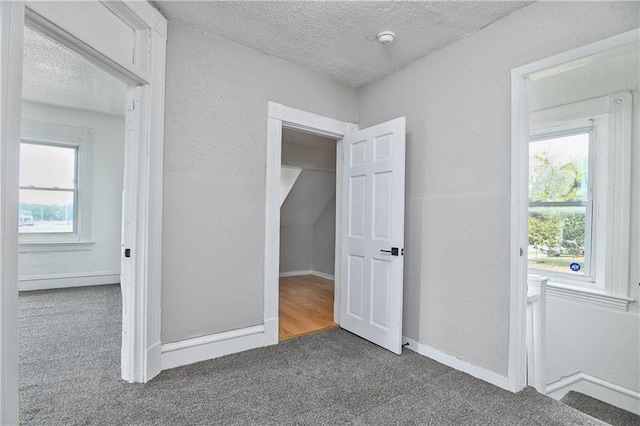 unfurnished bedroom with a textured ceiling and dark colored carpet