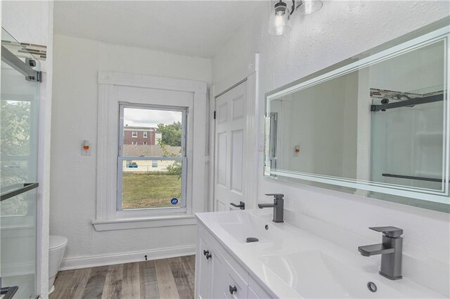 3229 Wayne Ave, Kansas City, MO 64109 - full bathroom featuring toilet, a sink, baseboards, and wood finished floors