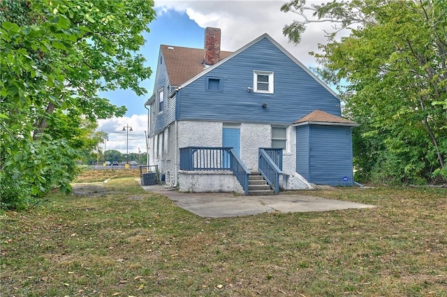 3229 Wayne Ave, Kansas City, MO 64109 - back of house with a chimney, central air condition unit, a yard, and a patio area