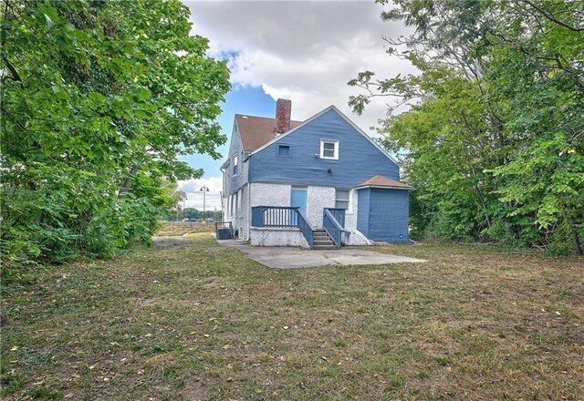 3229 Wayne Ave, Kansas City, MO 64109 - back of property featuring a patio, a chimney, and a yard