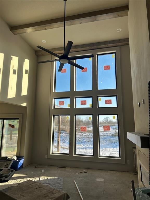 unfurnished living room featuring beamed ceiling and ceiling fan