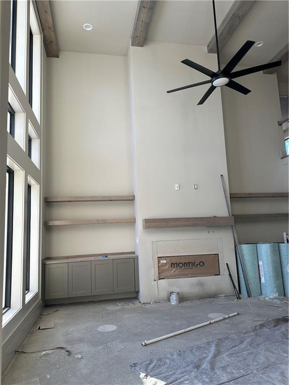 unfurnished living room featuring beam ceiling and a high ceiling