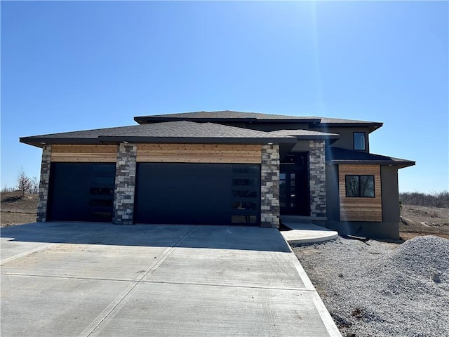 prairie-style home featuring concrete driveway, a garage, and stone siding