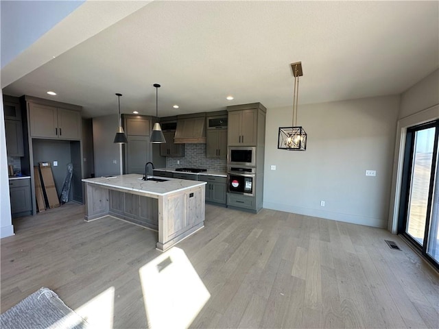 kitchen with tasteful backsplash, light wood-type flooring, gray cabinets, stainless steel appliances, and a sink