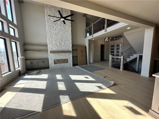 unfurnished living room with a stone fireplace, stairway, and wood finished floors