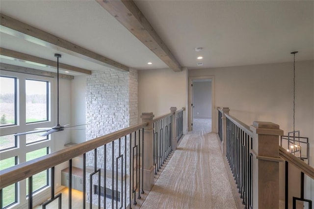 hall featuring beamed ceiling, an upstairs landing, an inviting chandelier, and a healthy amount of sunlight
