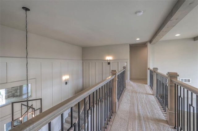 hall featuring a decorative wall, light colored carpet, visible vents, and recessed lighting