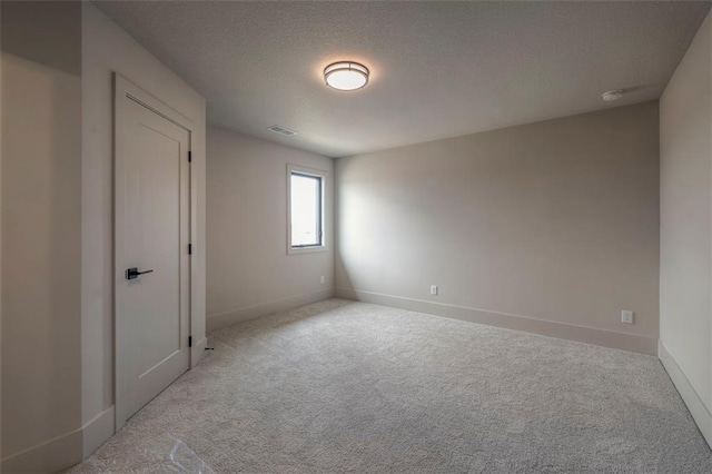 unfurnished room with a textured ceiling, carpet flooring, baseboards, and visible vents