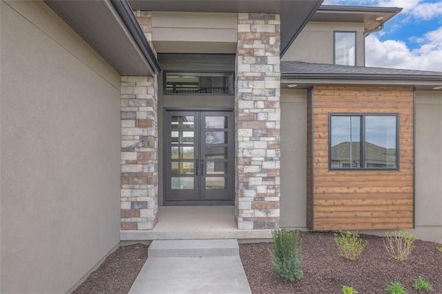 view of exterior entry featuring stone siding, french doors, and stucco siding