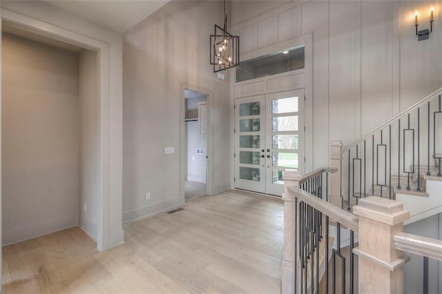 foyer entrance with stairway, baseboards, french doors, and wood finished floors