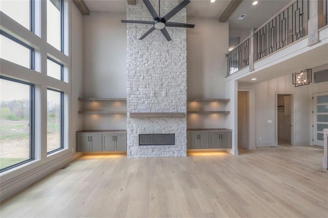 unfurnished living room with a ceiling fan, a towering ceiling, a wealth of natural light, and a fireplace