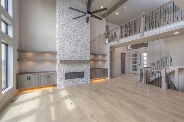 unfurnished living room with plenty of natural light, a ceiling fan, high vaulted ceiling, and a fireplace
