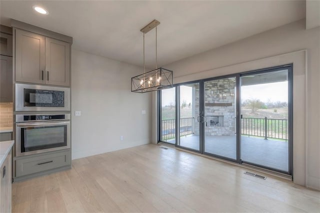 kitchen with built in microwave, oven, light wood-style floors, gray cabinetry, and visible vents