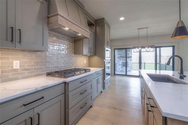 kitchen with stainless steel appliances, a sink, a healthy amount of sunlight, custom exhaust hood, and gray cabinets