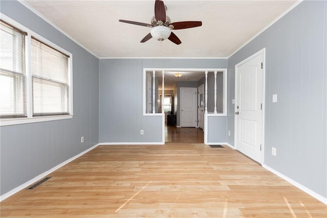 spare room with crown molding, a healthy amount of sunlight, and light hardwood / wood-style flooring