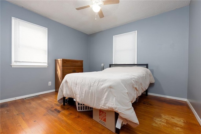 bedroom featuring hardwood / wood-style flooring, a textured ceiling, and ceiling fan