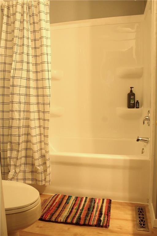 bathroom with shower / tub combo, wood-type flooring, and toilet