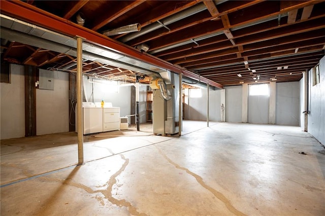 basement featuring separate washer and dryer, heating unit, and electric panel