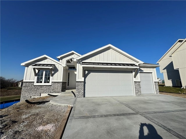 view of front of property featuring a garage, concrete driveway, metal roof, a standing seam roof, and board and batten siding