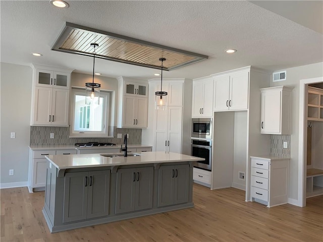 kitchen with stainless steel appliances, a center island with sink, and white cabinets