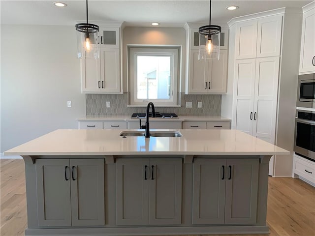 kitchen featuring appliances with stainless steel finishes, light countertops, a center island with sink, and a sink