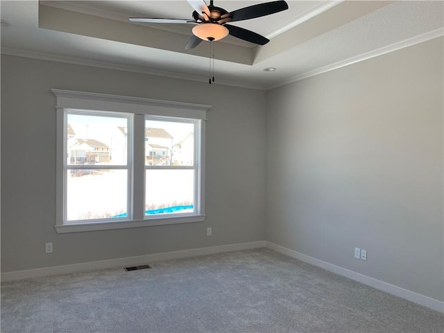 spare room featuring ornamental molding, a tray ceiling, visible vents, and baseboards