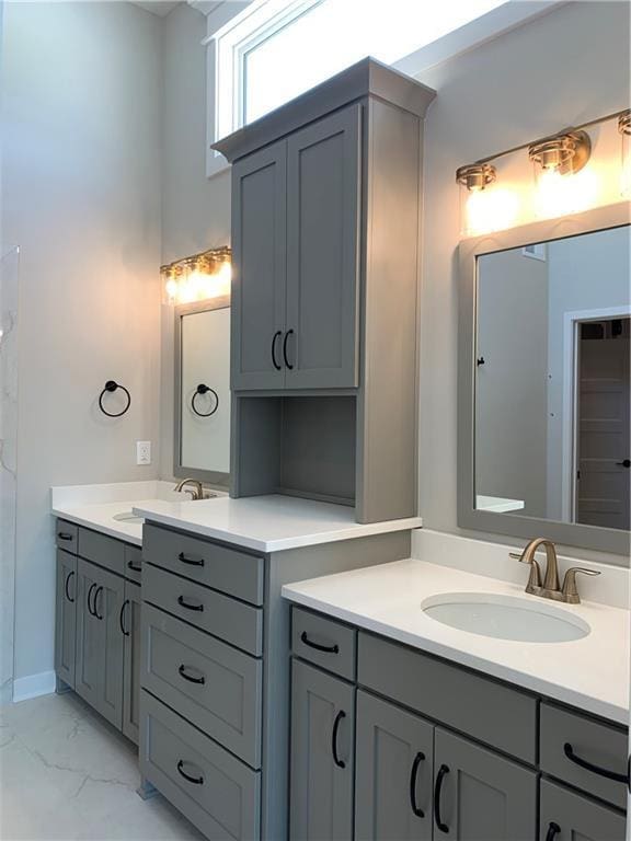 bathroom featuring marble finish floor, two vanities, and a sink