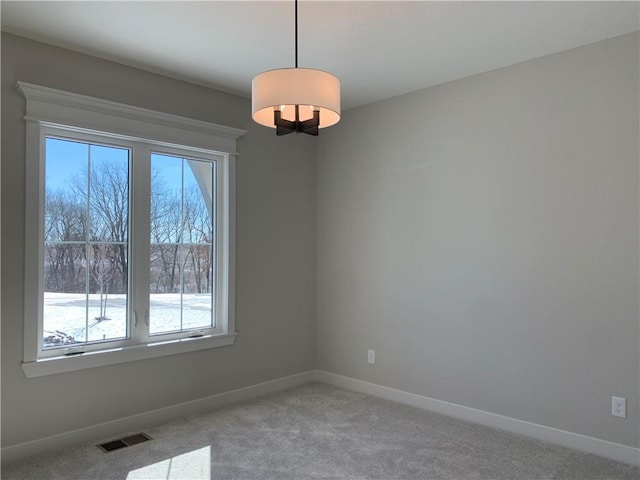 spare room featuring light colored carpet, visible vents, and baseboards