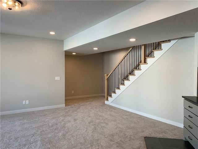 below grade area with carpet, recessed lighting, a textured ceiling, baseboards, and stairs