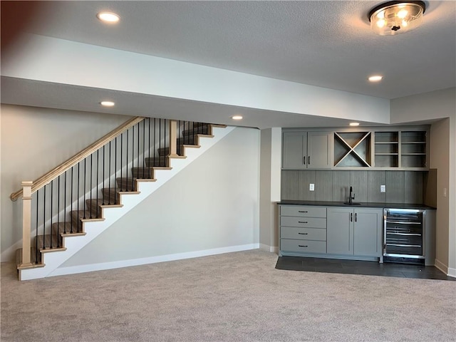 bar with indoor wet bar, recessed lighting, stairway, a sink, and beverage cooler