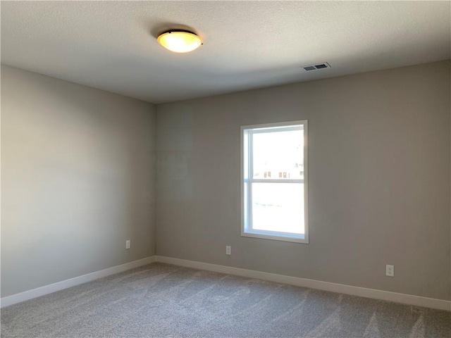 unfurnished room featuring carpet, visible vents, a textured ceiling, and baseboards