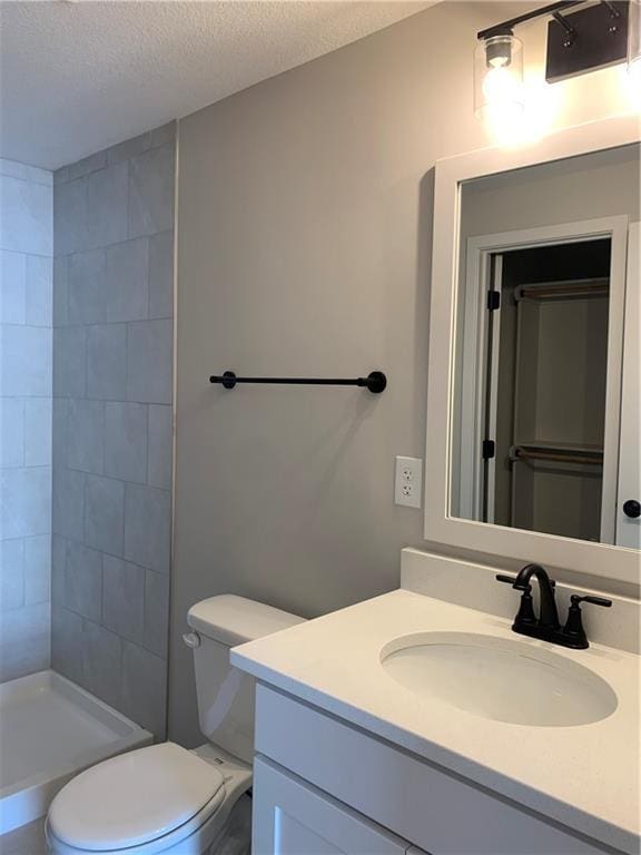 full bath featuring a textured ceiling, toilet, a shower stall, and vanity