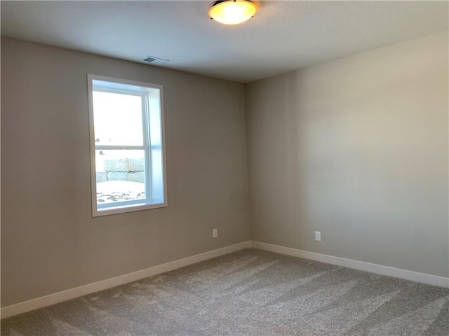 empty room with carpet flooring, visible vents, and baseboards