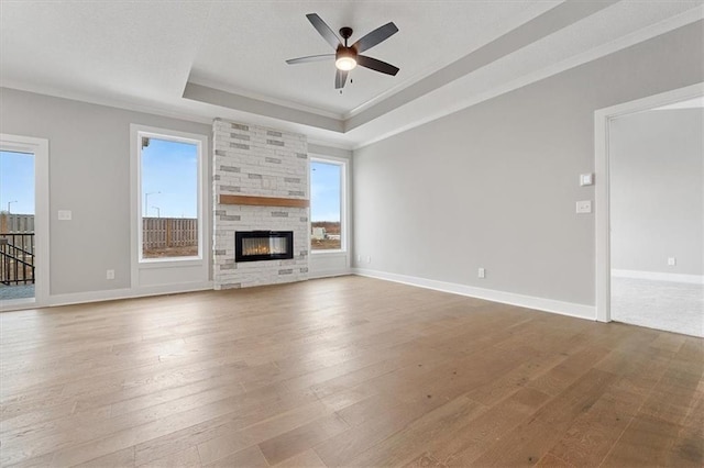 unfurnished living room with hardwood / wood-style flooring, ceiling fan, crown molding, and a raised ceiling