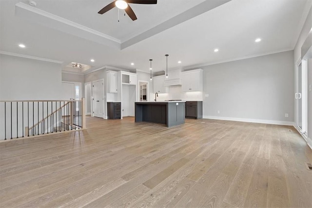 kitchen featuring light hardwood / wood-style flooring, decorative light fixtures, crown molding, white cabinets, and a spacious island