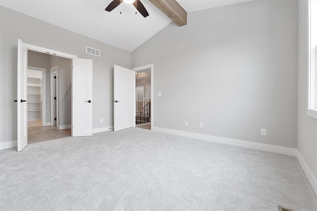 unfurnished bedroom featuring light carpet, vaulted ceiling with beams, and ceiling fan