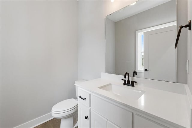 bathroom with hardwood / wood-style flooring, toilet, and vanity