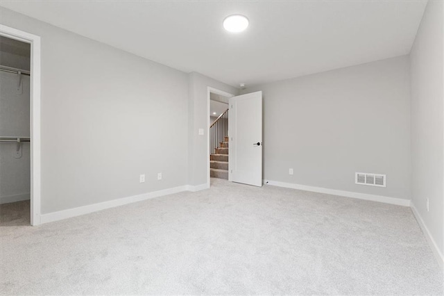 unfurnished bedroom with light carpet, a closet, and a spacious closet