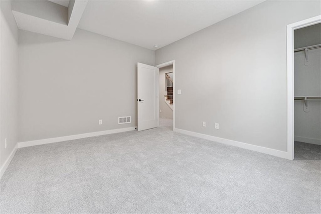 unfurnished bedroom with light carpet, a walk in closet, and a closet