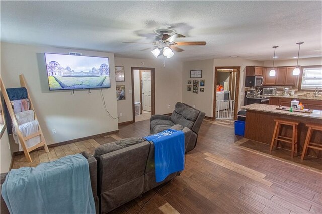 living room with ceiling fan, a textured ceiling, and dark hardwood / wood-style floors