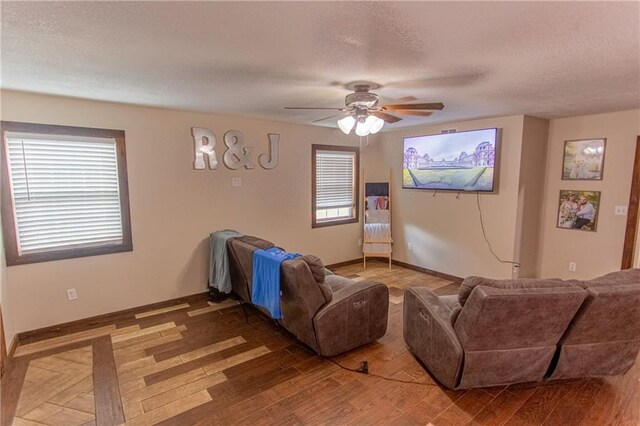 living room featuring wood-type flooring, ceiling fan, and a textured ceiling