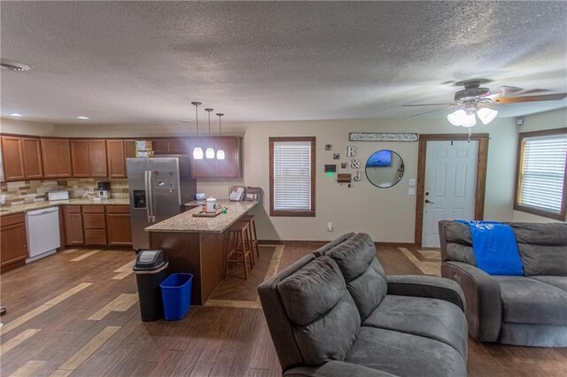 interior space with pendant lighting, dishwasher, dark wood-type flooring, ceiling fan, and stainless steel fridge