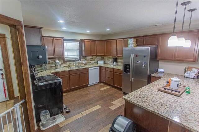 kitchen featuring pendant lighting, white dishwasher, sink, dark wood-type flooring, and stainless steel fridge with ice dispenser